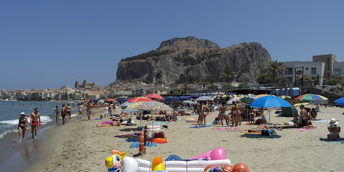 Cefalù'da kalabalık yaz plajı ve kasaba