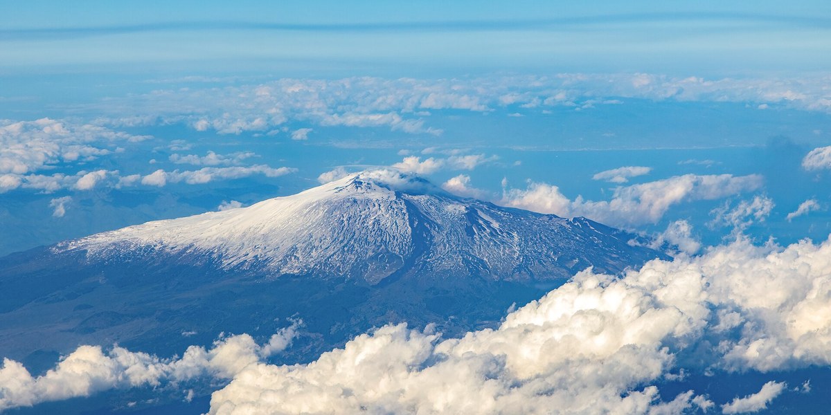 Bulutların üstünde Etna'nın karlı zirvesi