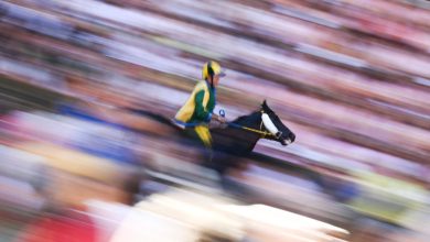 Palio di Siena at yarışında çamurlu pistte tam hızla koşan at ve yeşil-sarı renkli jokey